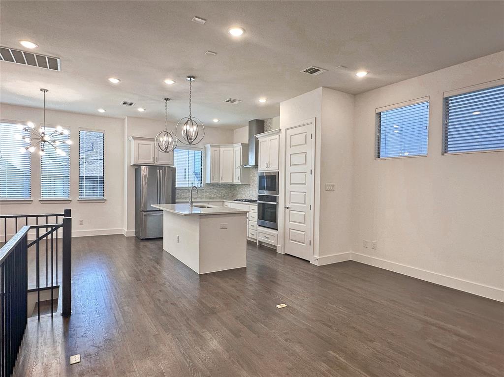 a large kitchen with stainless steel appliances kitchen island a large counter top and a wooden floors