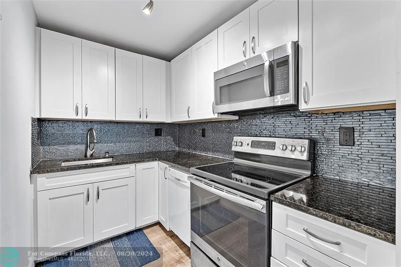 a kitchen with stainless steel appliances granite countertop a sink and a stove