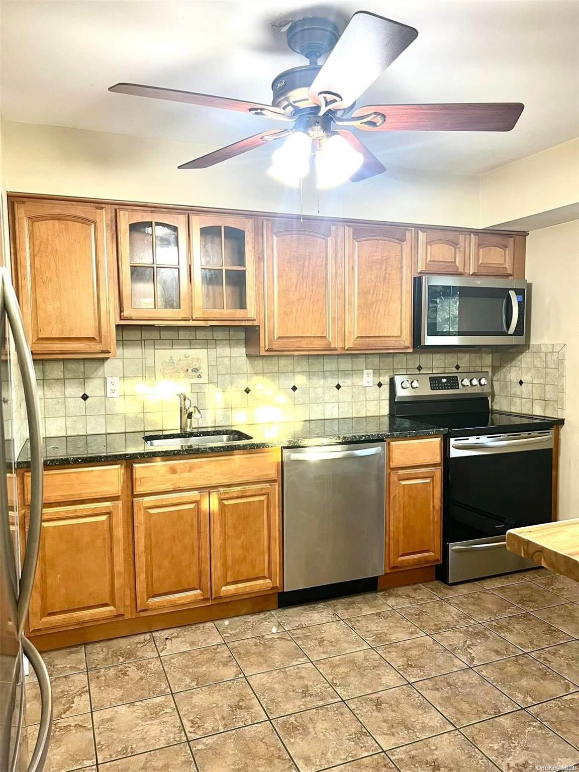 a kitchen with granite countertop a stove a sink and a microwave