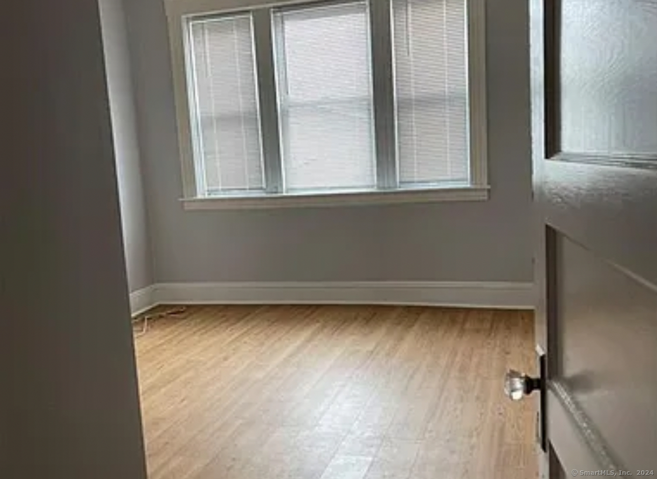 a view of a small space with wooden floor and a window