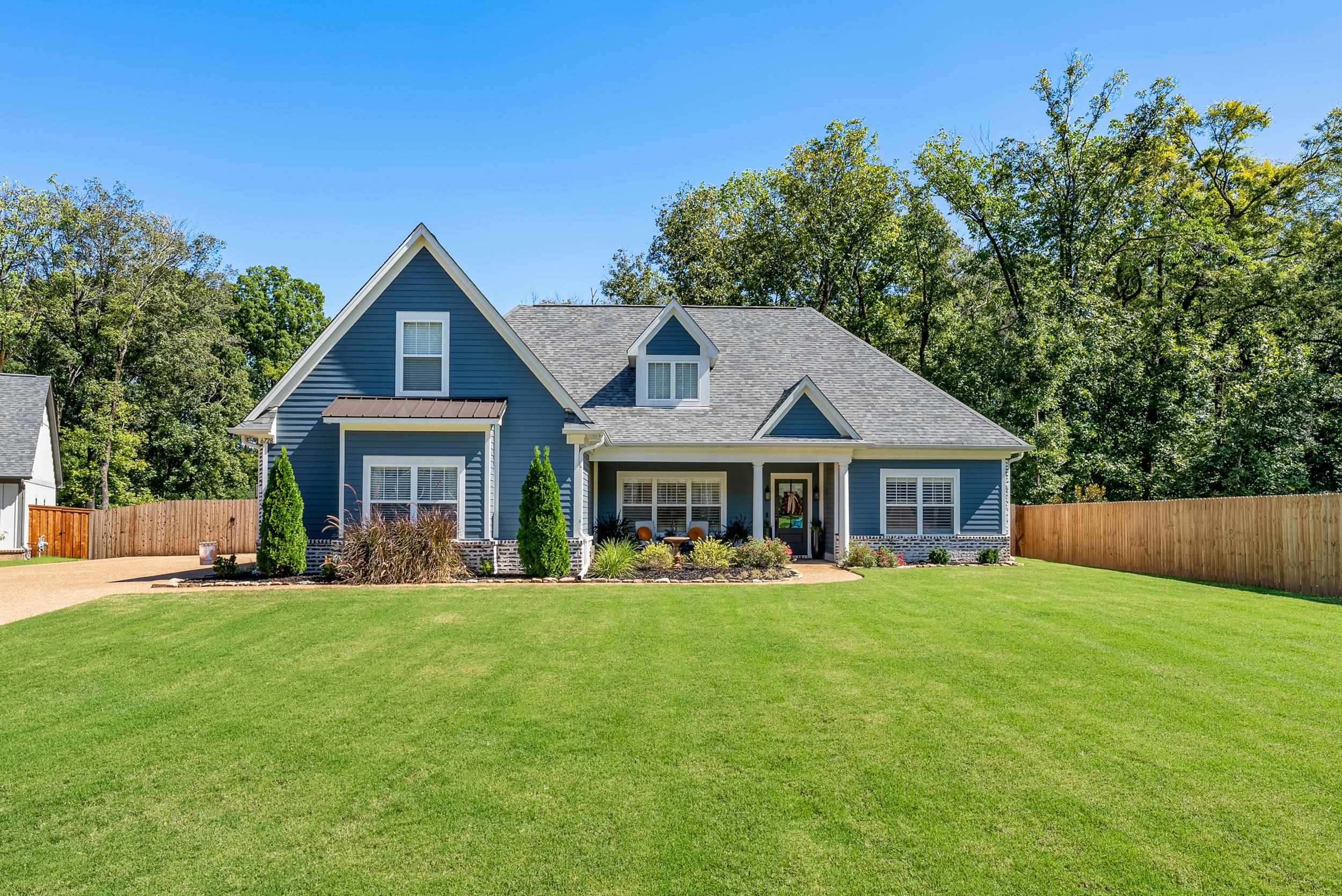 a front view of a house with a yard and trees