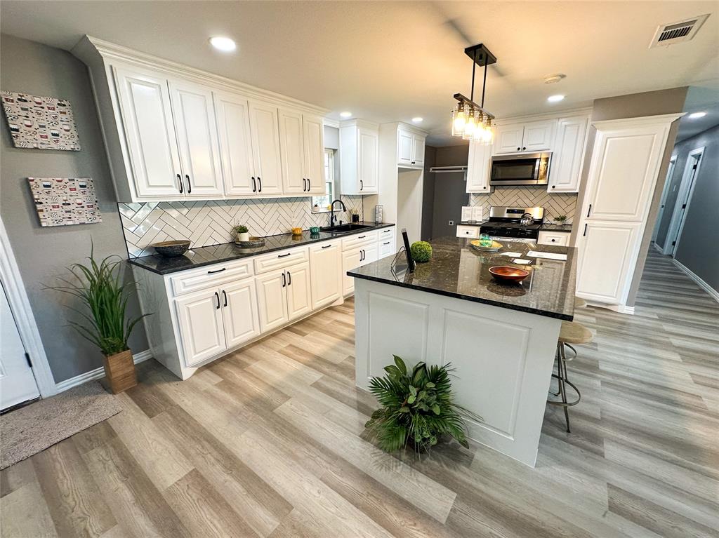 a kitchen with stainless steel appliances kitchen island granite countertop a stove a sink and a refrigerator