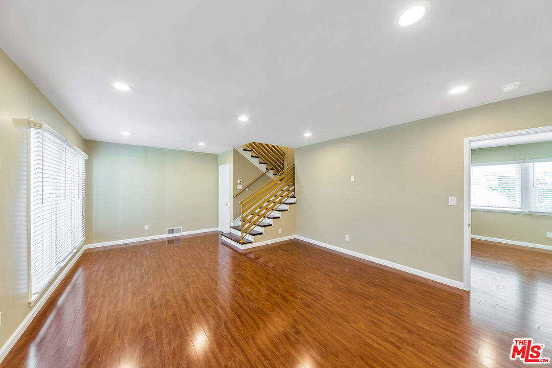 a view of an empty room with wooden floor and windows