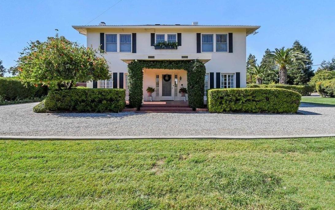 a front view of a house with a yard and potted plants