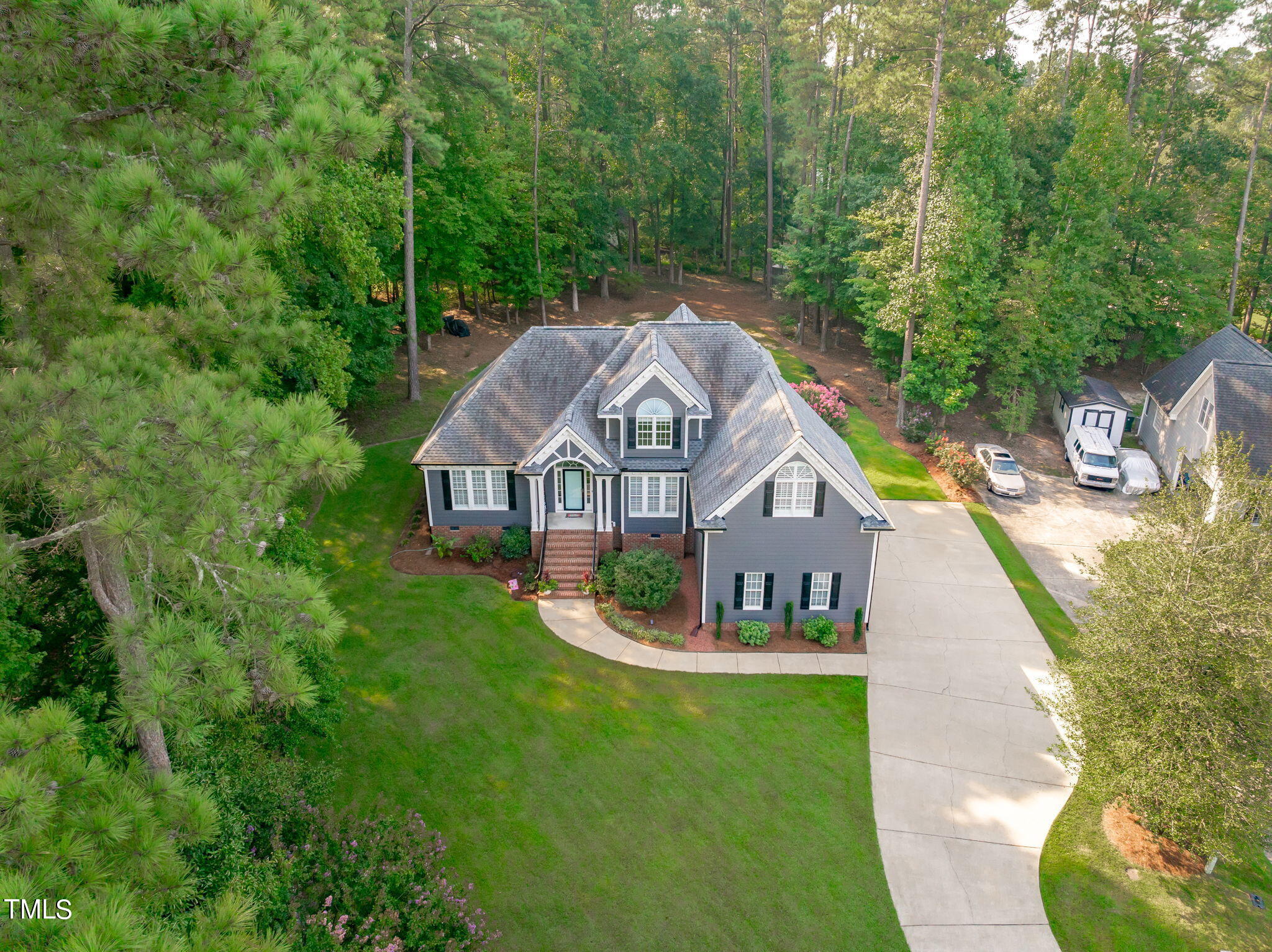 a view of a house with a small yard and large trees