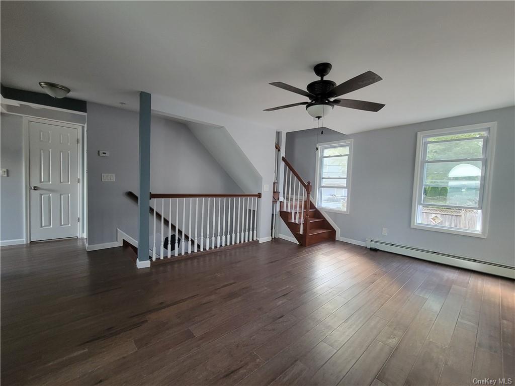 a view of a livingroom with wooden floor a ceiling fan and windows