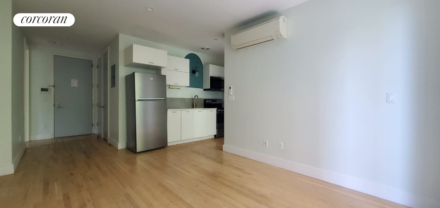 a view of a refrigerator in kitchen and an empty room