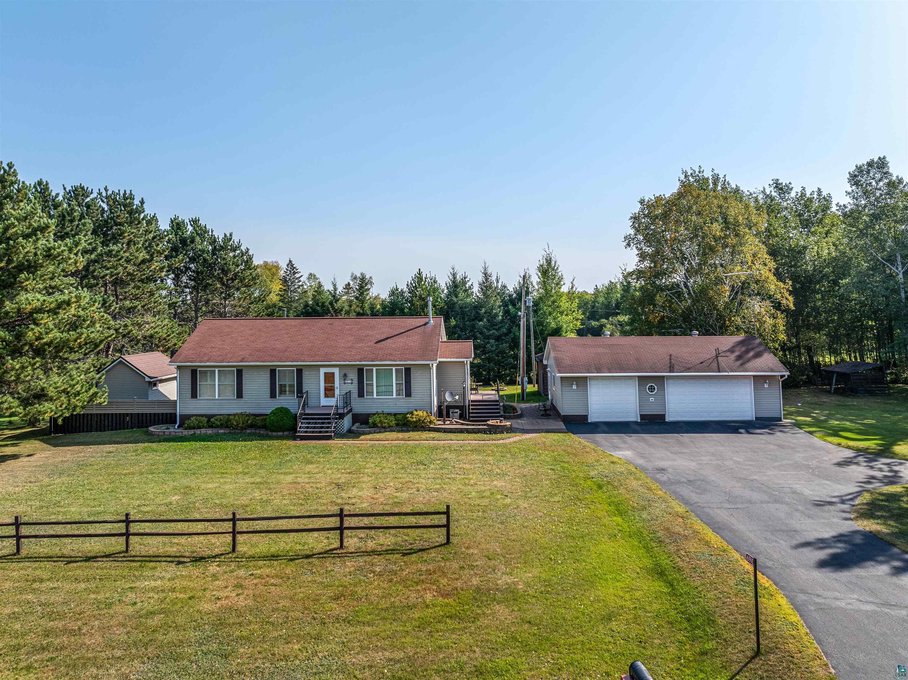 Ranch-style home featuring a garage, a front yard, and an outbuilding