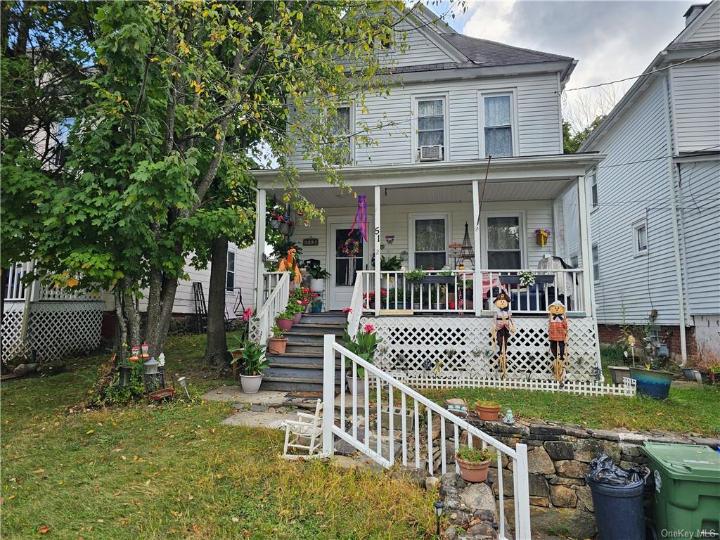 View of front of property featuring a front yard, cooling unit, and covered porch