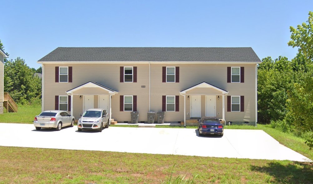 a front view of a house with a yard and car parked