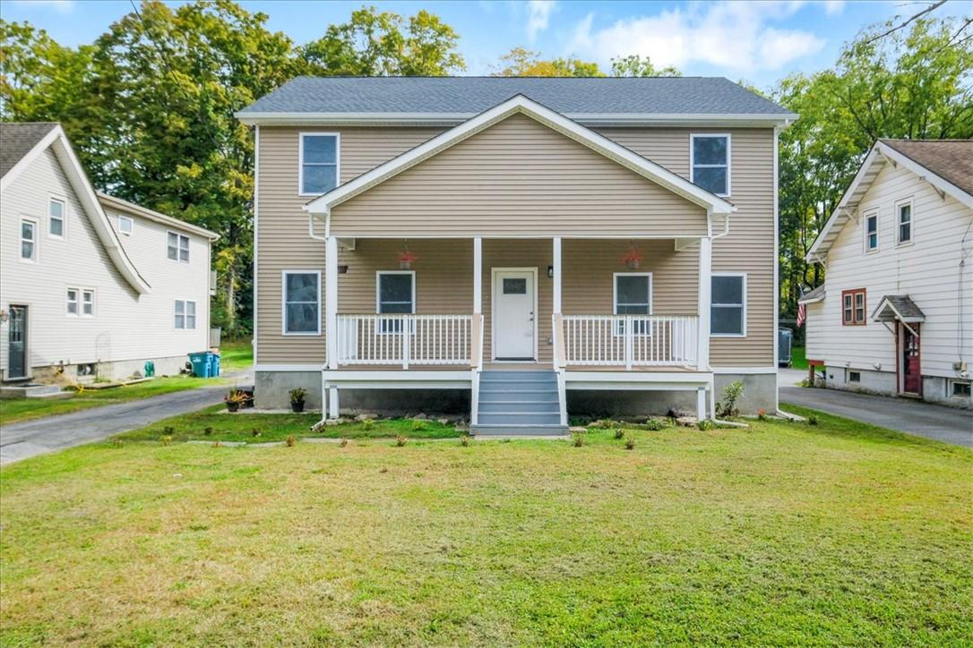 View of front facade featuring a front yard and covered porch