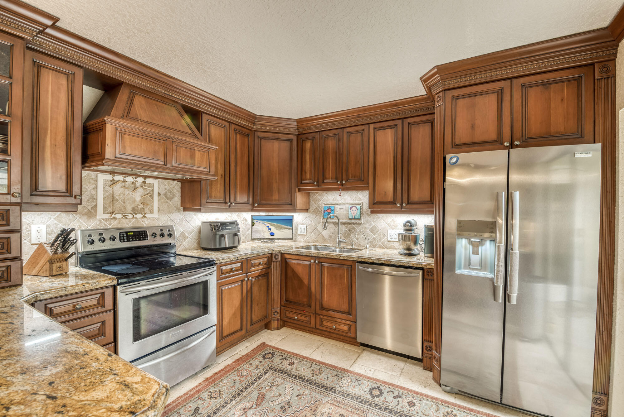 a kitchen with granite countertop stainless steel appliances a refrigerator stove top oven and sink