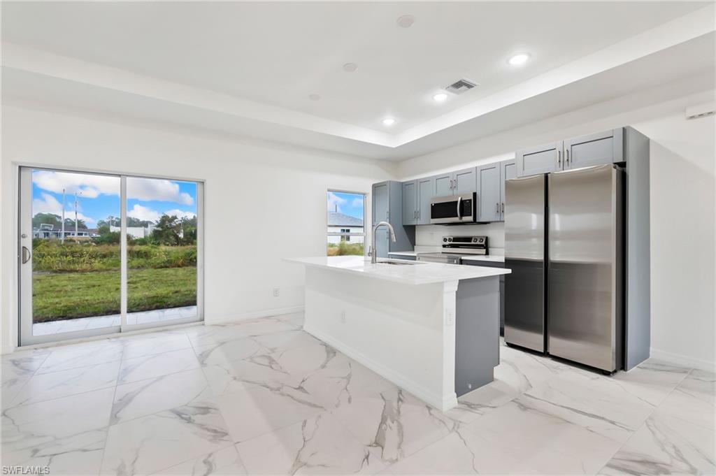 Kitchen with sink, stainless steel appliances, a wealth of natural light, and an island with sink