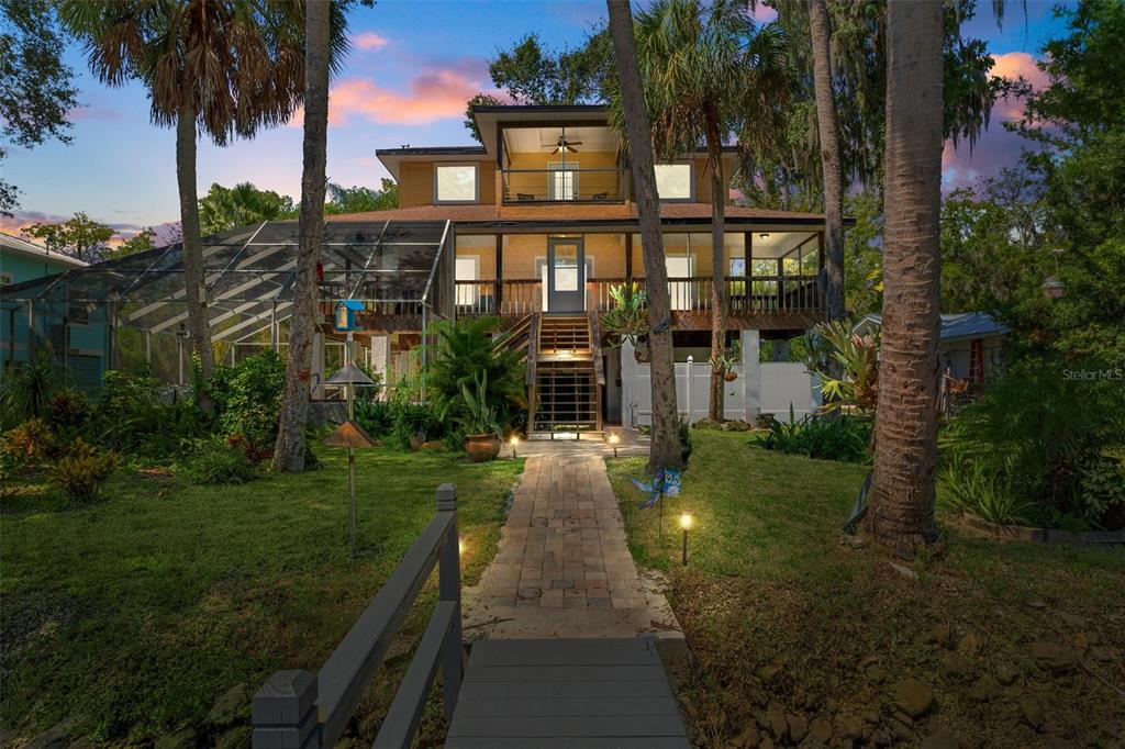 a view of a house next to a yard with plants and palm trees