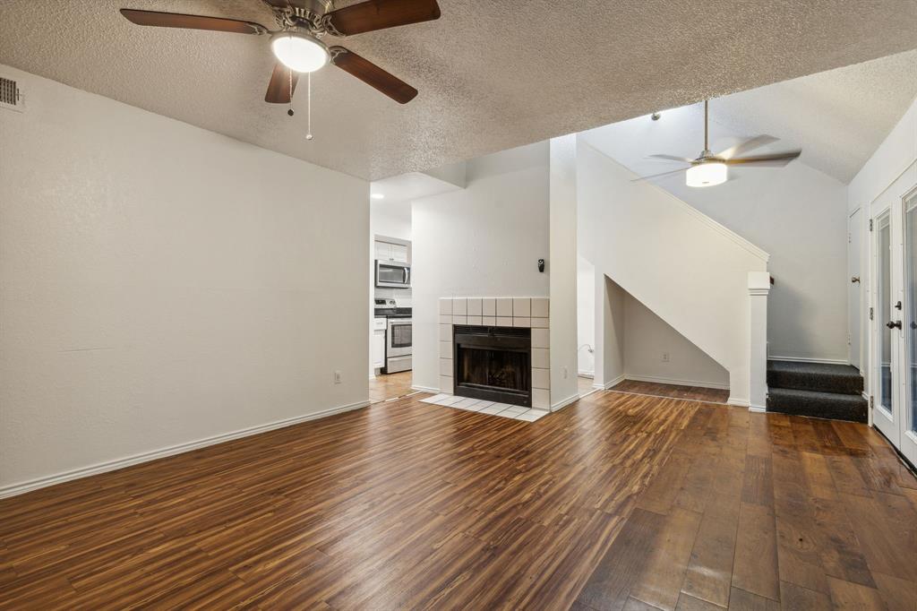 a view of empty room with wooden floor fan and window