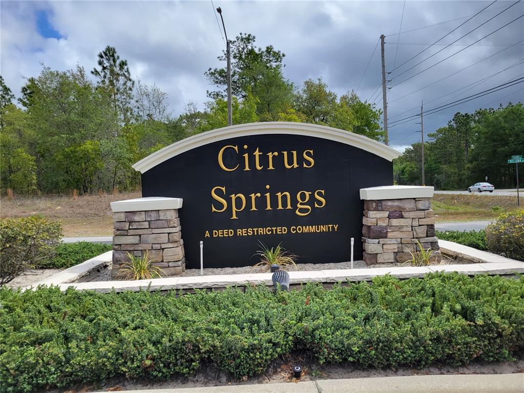 a sign board with a house and a yard in the background