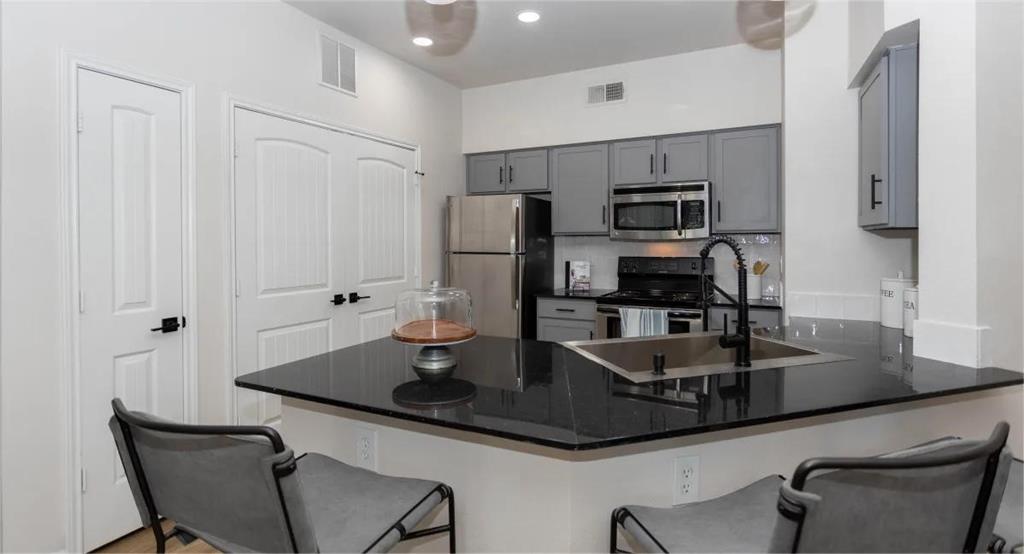 a kitchen with granite countertop a sink cabinets and stainless steel appliances