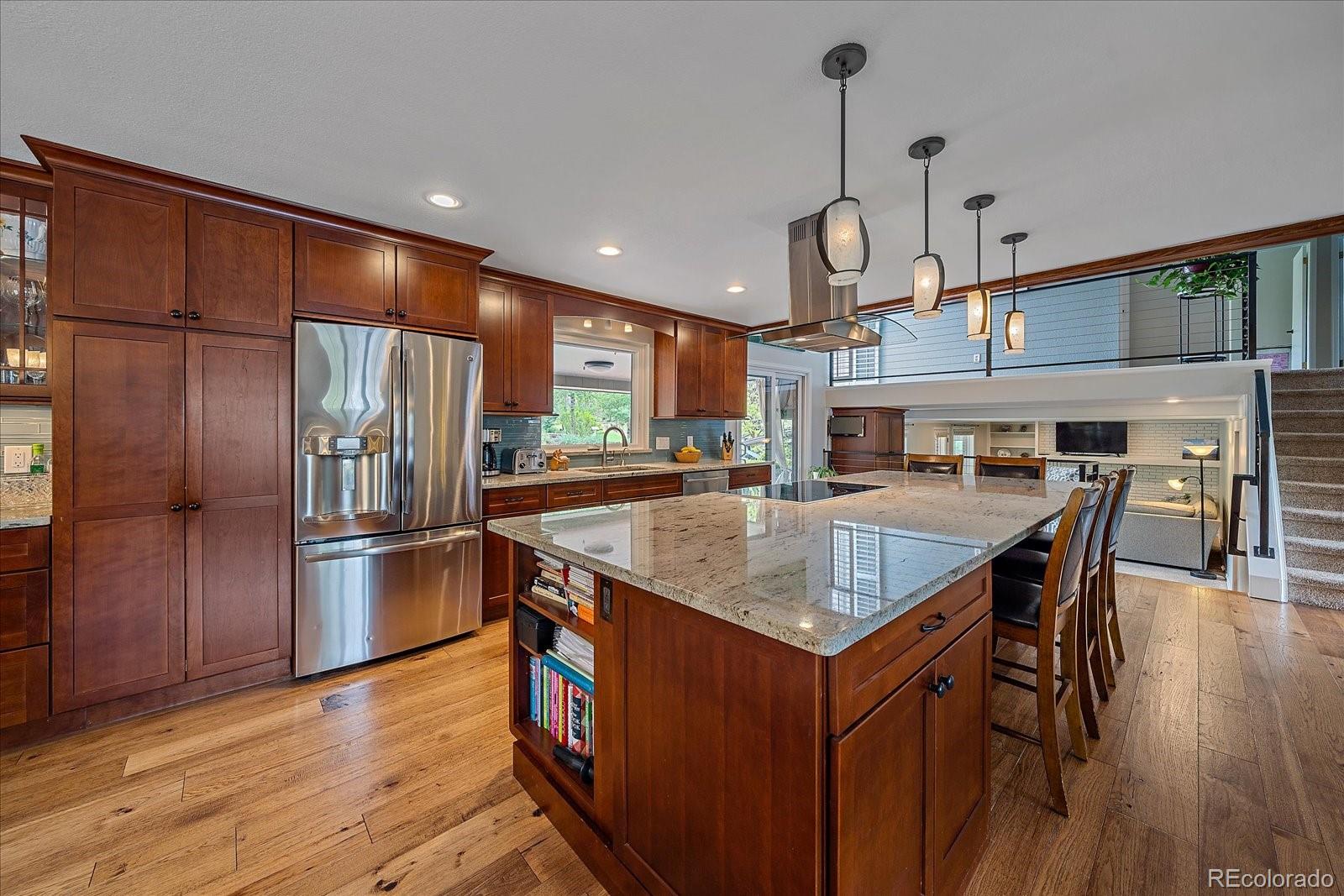 a kitchen with stainless steel appliances granite countertop a kitchen island a stove a refrigerator a oven a dining table and chairs with wooden floor