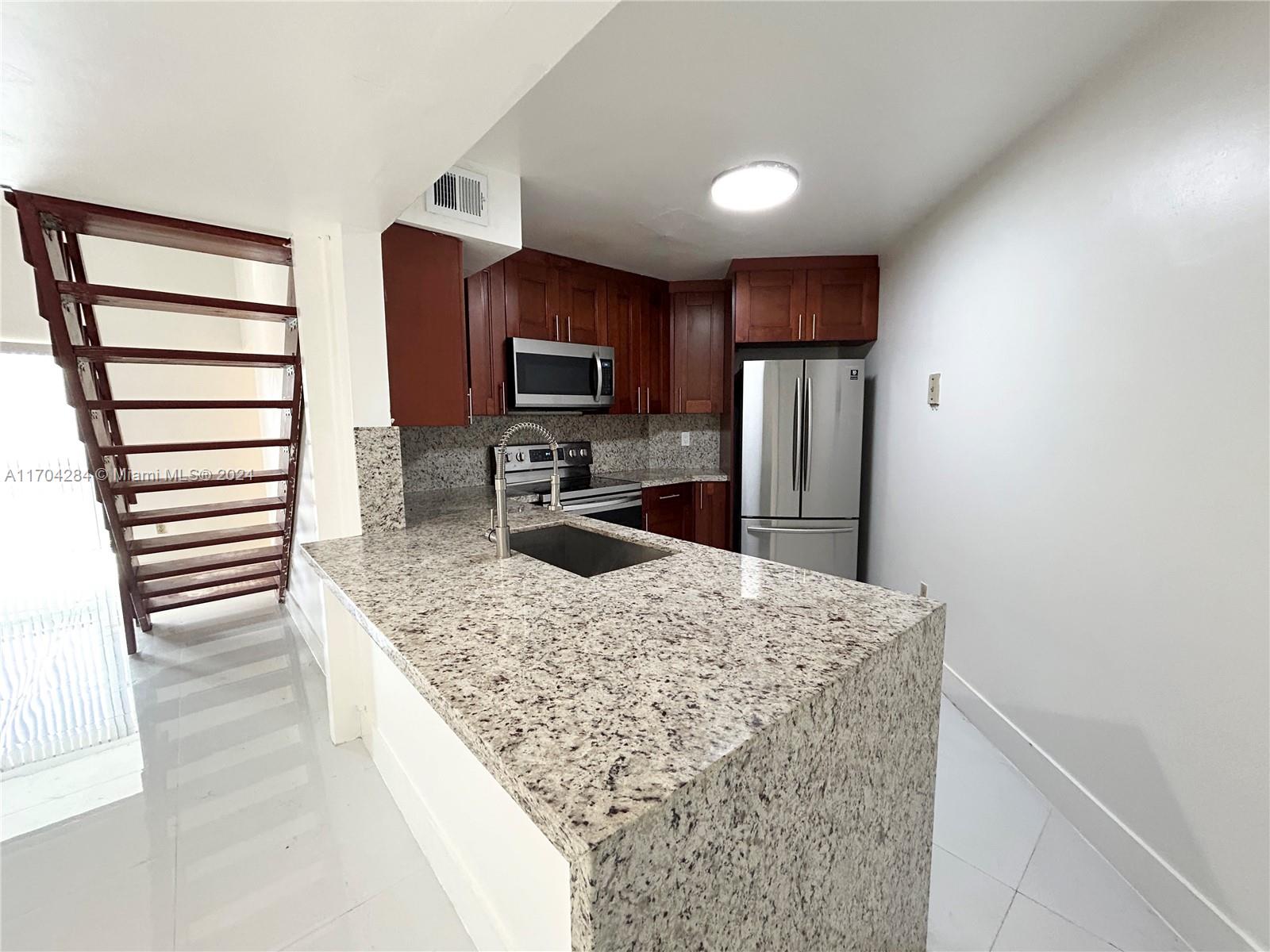 a kitchen with stainless steel appliances kitchen island granite countertop a refrigerator stove and oven