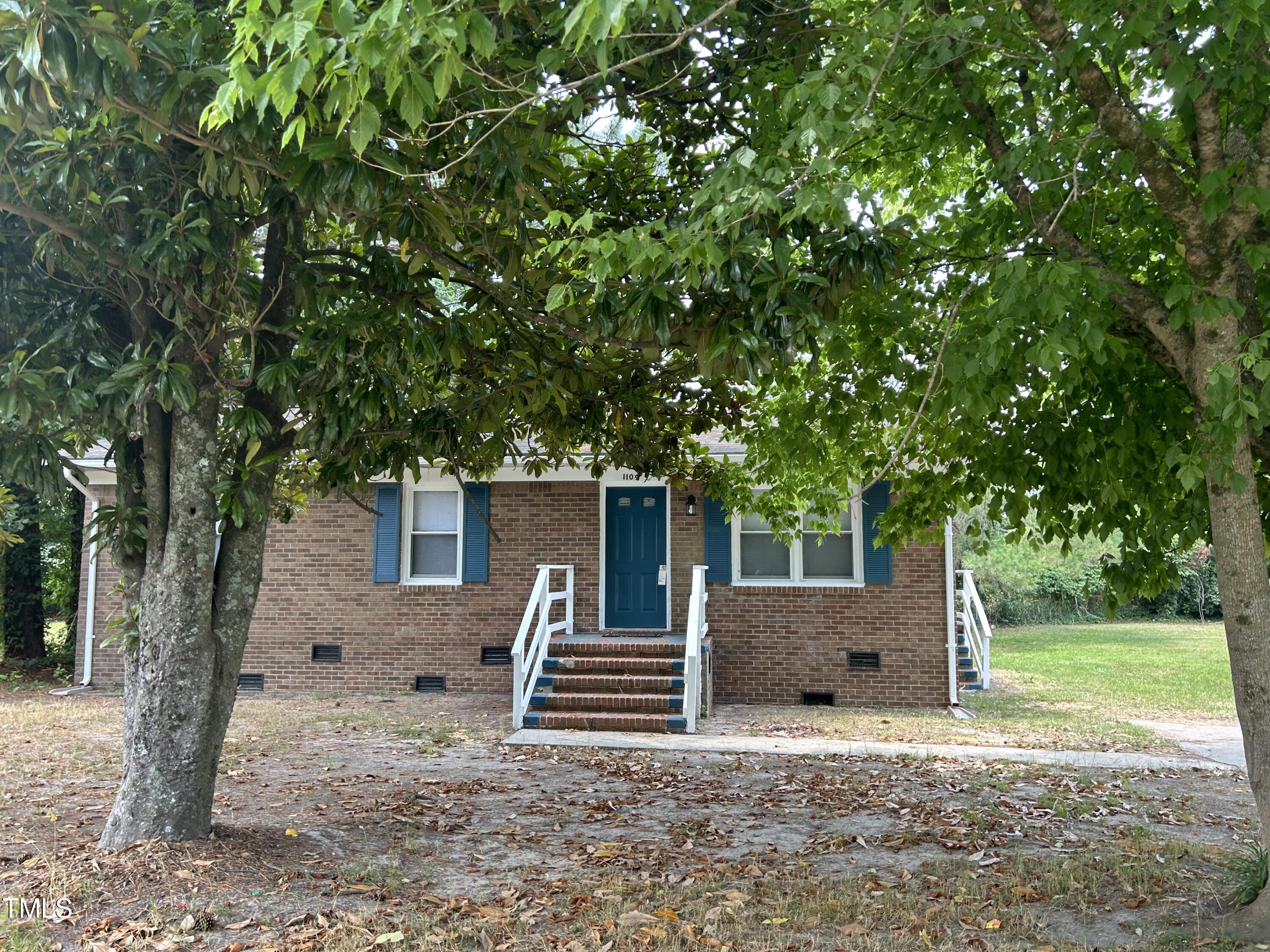 a backyard of a house with barbeque oven and trees