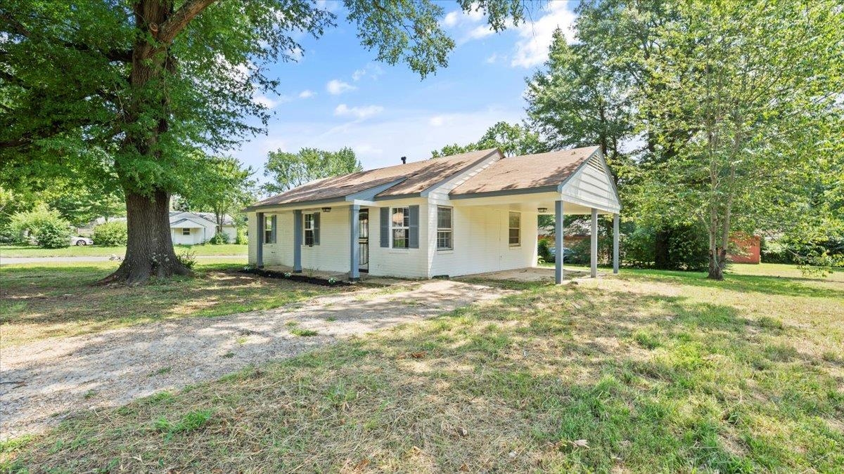 a view of a house with a yard and large tree