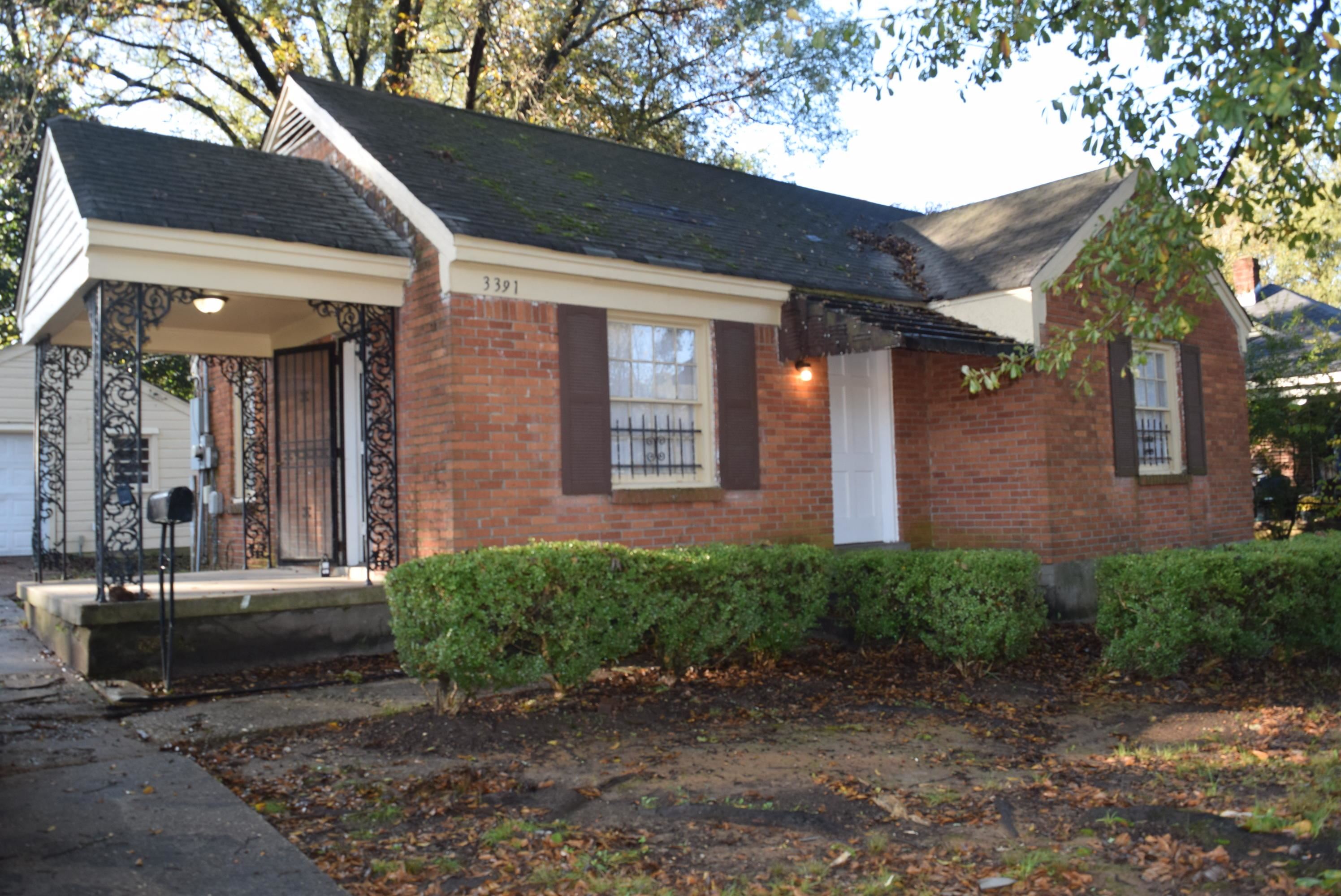 a view of a brick house with many windows next to a yard