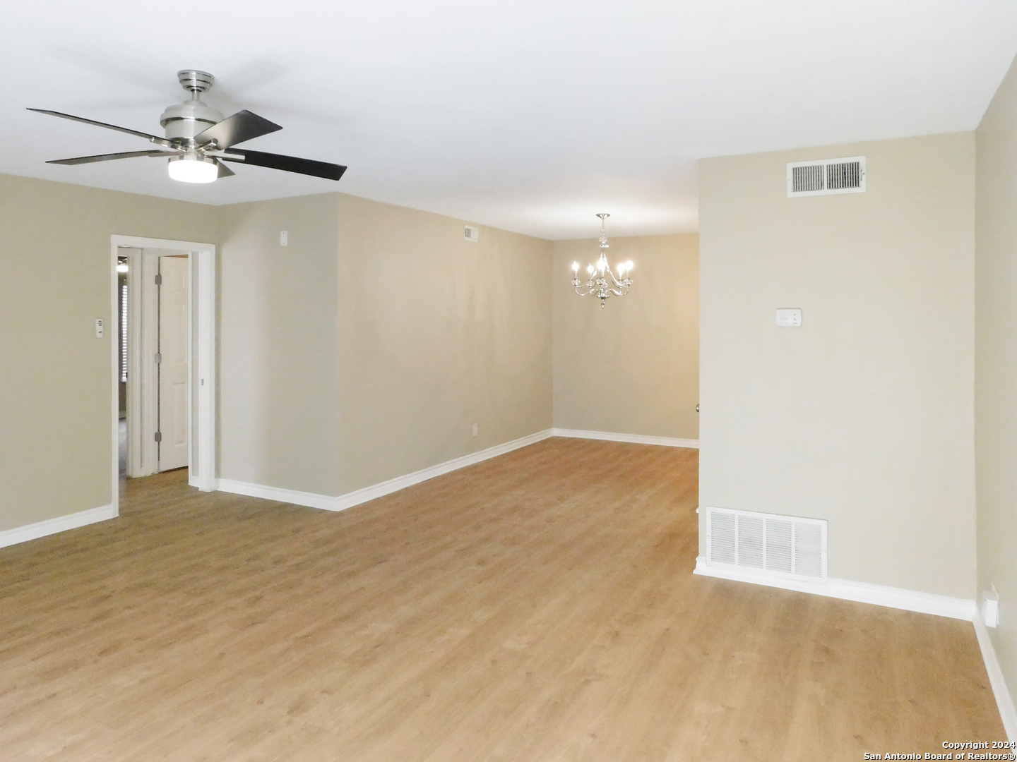 a view of an empty room with a chandelier fan