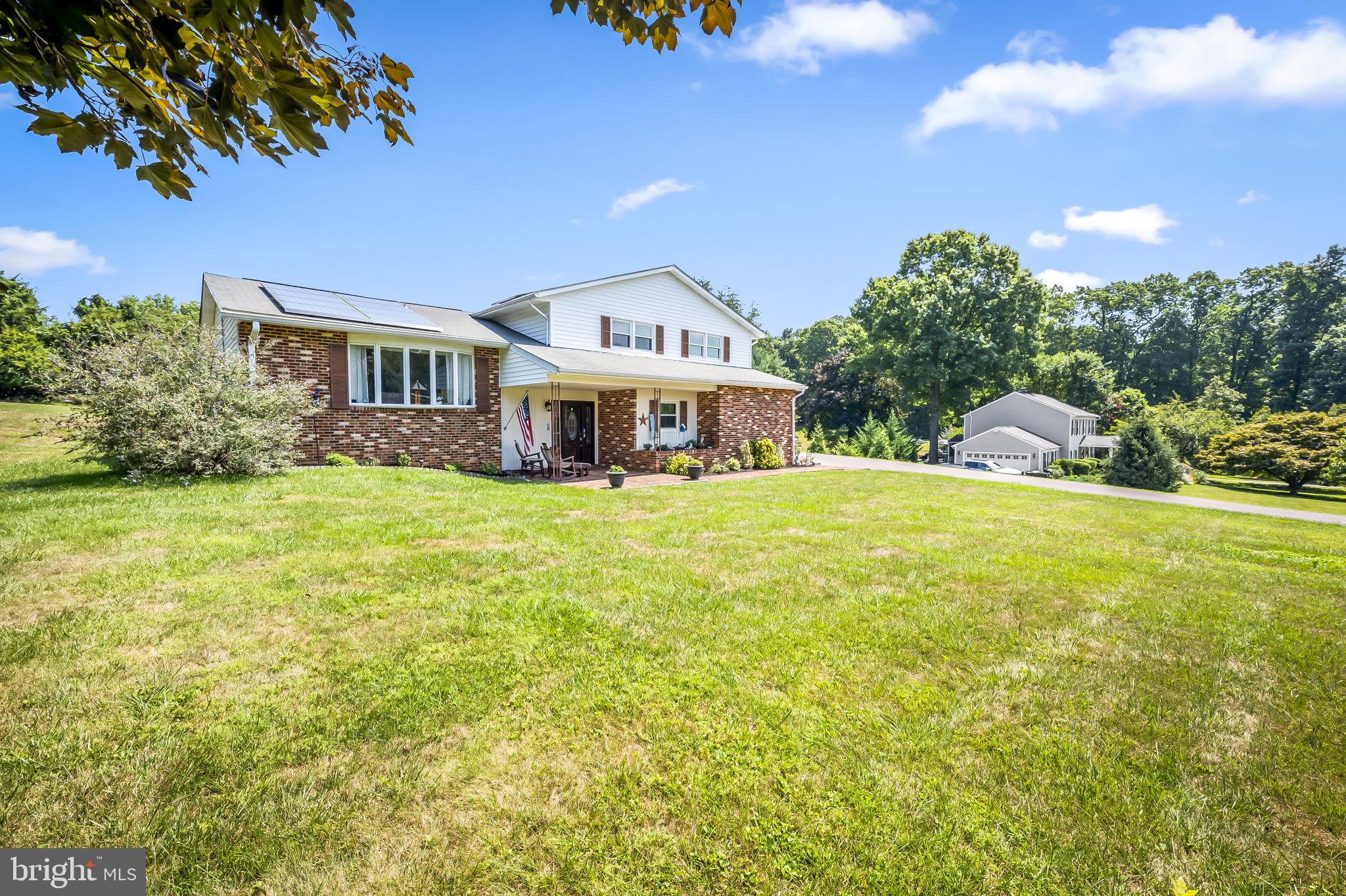 a view of a house with a big yard and large trees