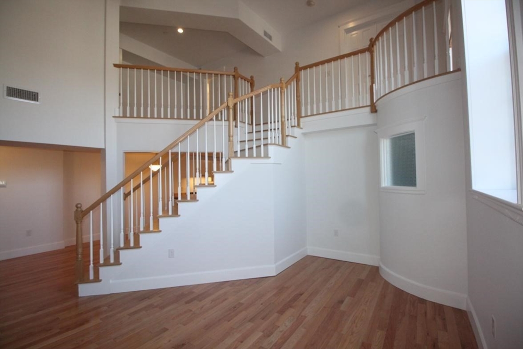 a view of staircase with wooden floor and white walls