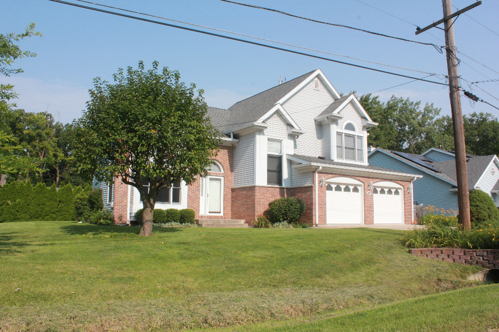 a view of a white house next to a yard with big trees