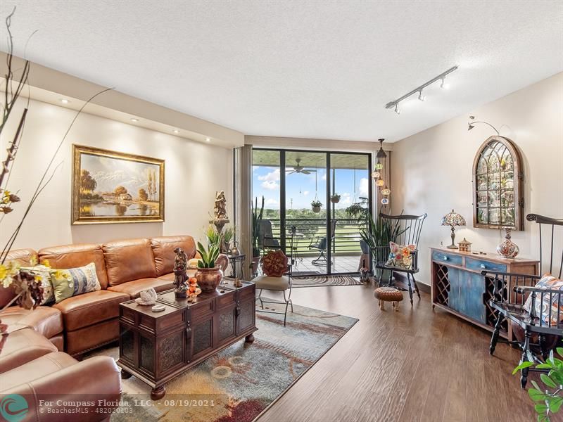 a living room with furniture floor to ceiling window and wooden floor