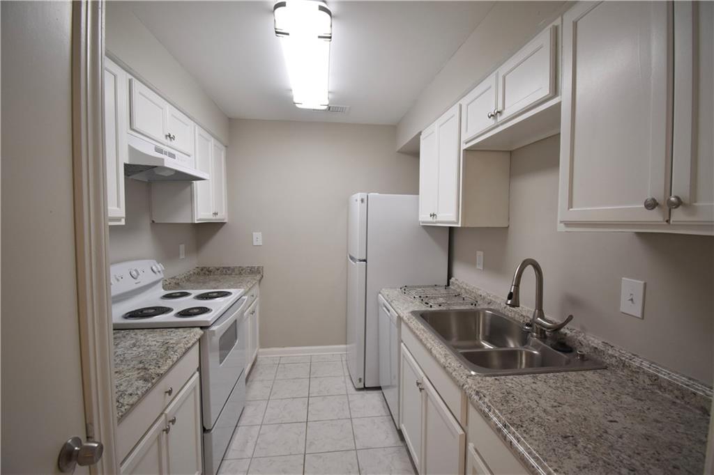 a kitchen with stainless steel appliances granite countertop a sink stove refrigerator and cabinets