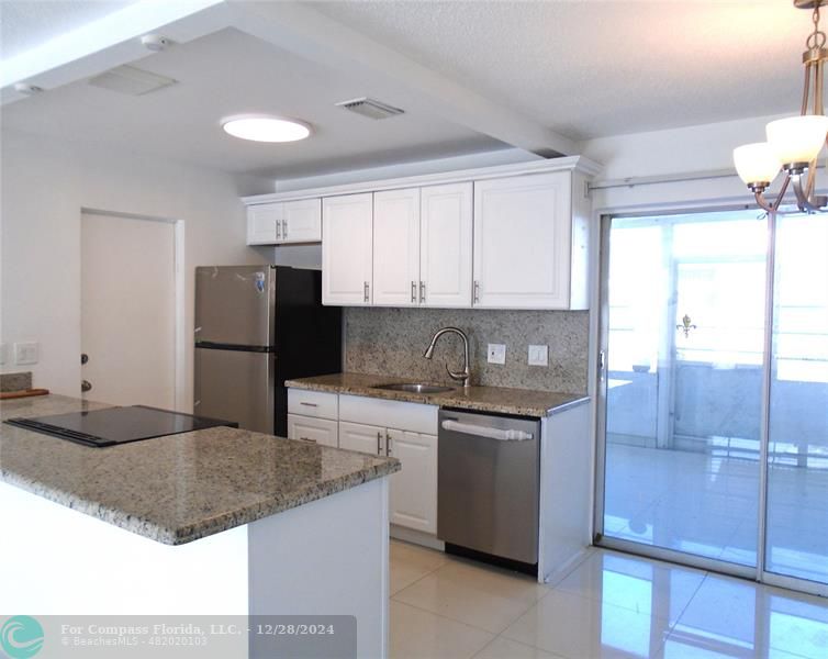 a kitchen with kitchen island granite countertop a sink stainless steel appliances and cabinets