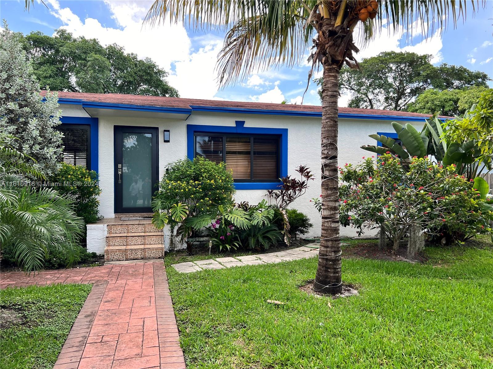 a front view of a house with a yard and potted plants