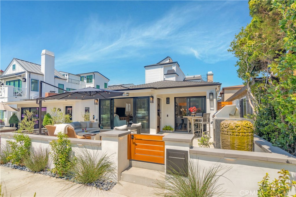 a view of a patio with couches table and chairs with wooden fence and plants