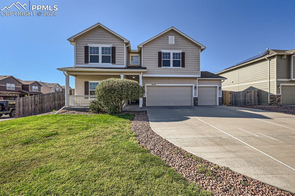 View of property featuring covered porch, a front yard, and a garage