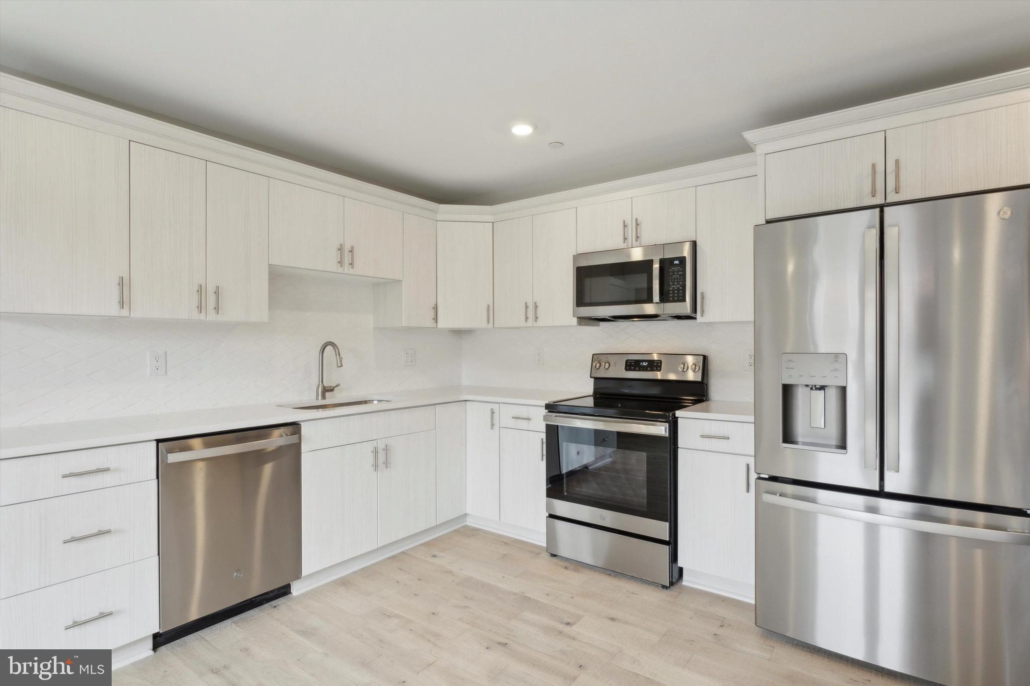 a kitchen with cabinets stainless steel appliances and a sink