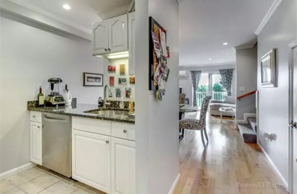 a kitchen with white cabinets and wooden floor