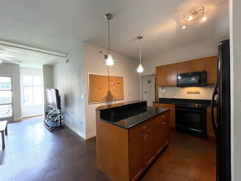 a kitchen with kitchen island granite countertop a refrigerator and a stove top oven