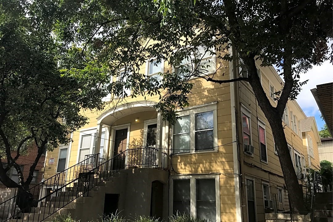 a front view of a residential apartment building with a tree