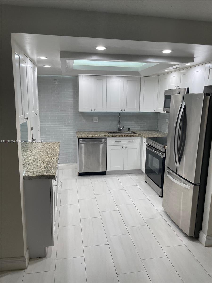 a kitchen with stainless steel appliances granite countertop a refrigerator and a sink