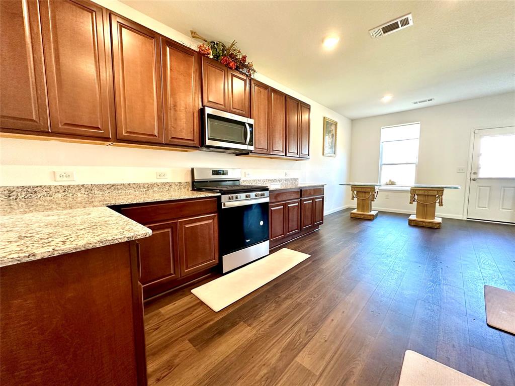 a kitchen with stainless steel appliances granite countertop wooden cabinets a stove top oven a sink and dishwasher