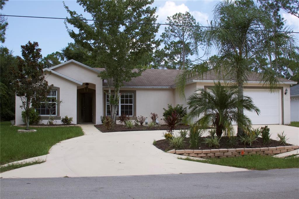 a front view of a house with garden and trees