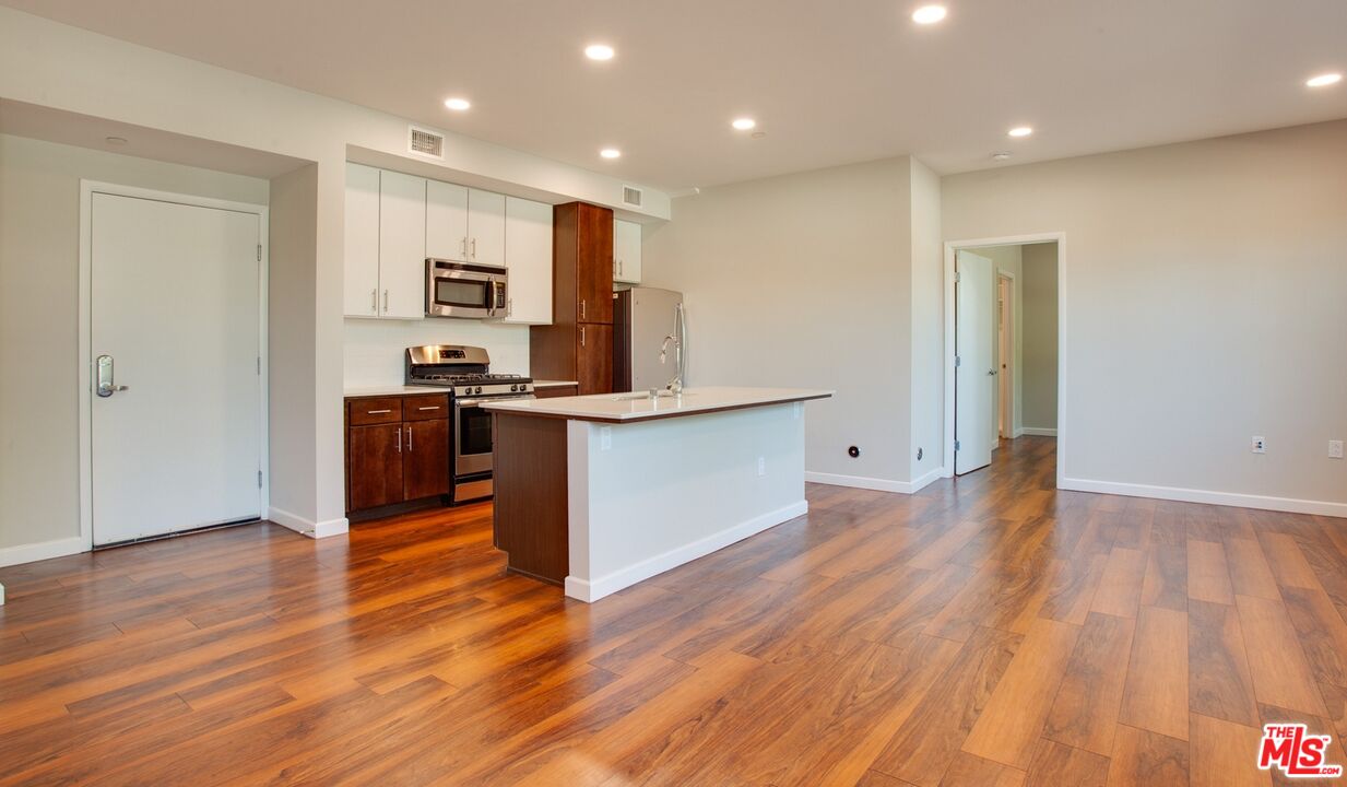 a view of kitchen with stainless steel appliances granite countertop a stove top oven a sink and a microwave