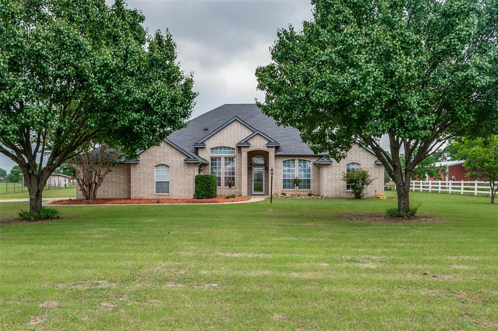 a front view of a house with a yard and trees