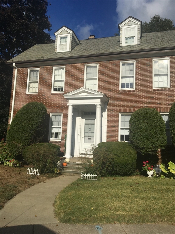 a view of a brick house with many windows and a yard