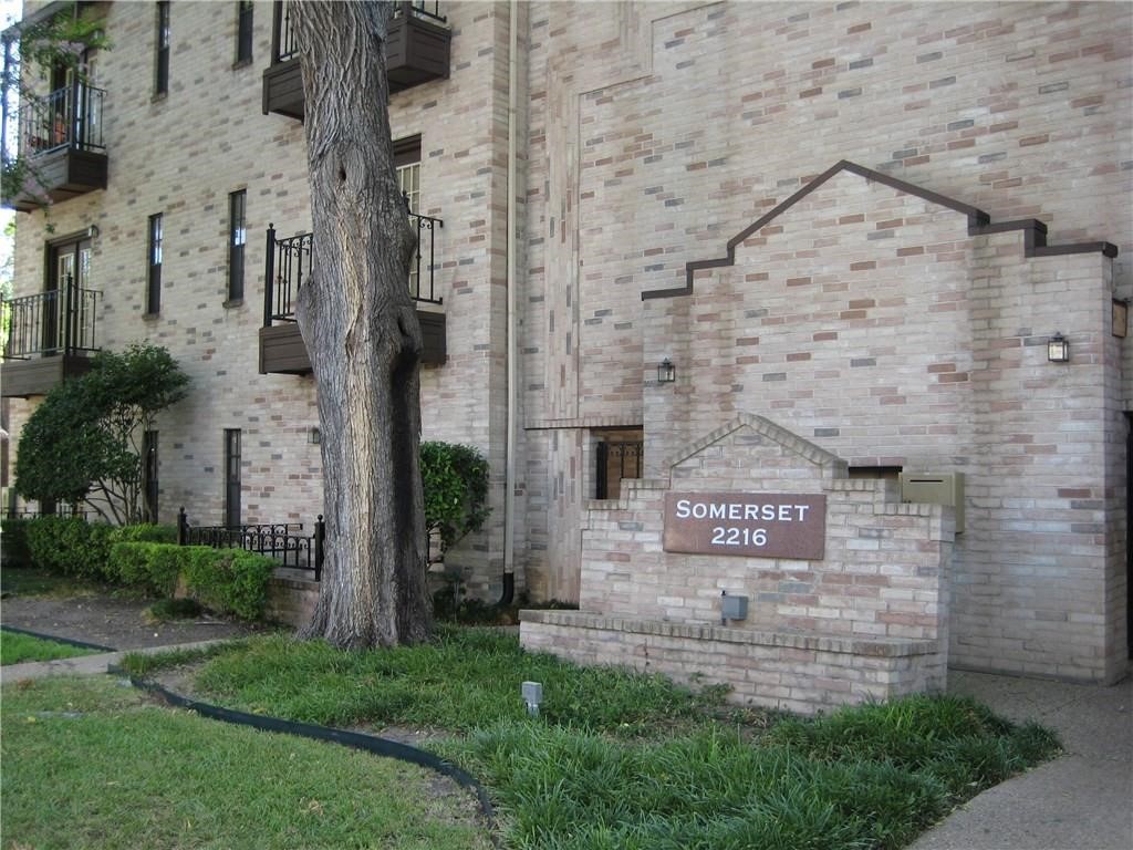 front view of a brick house with a yard and a large tree