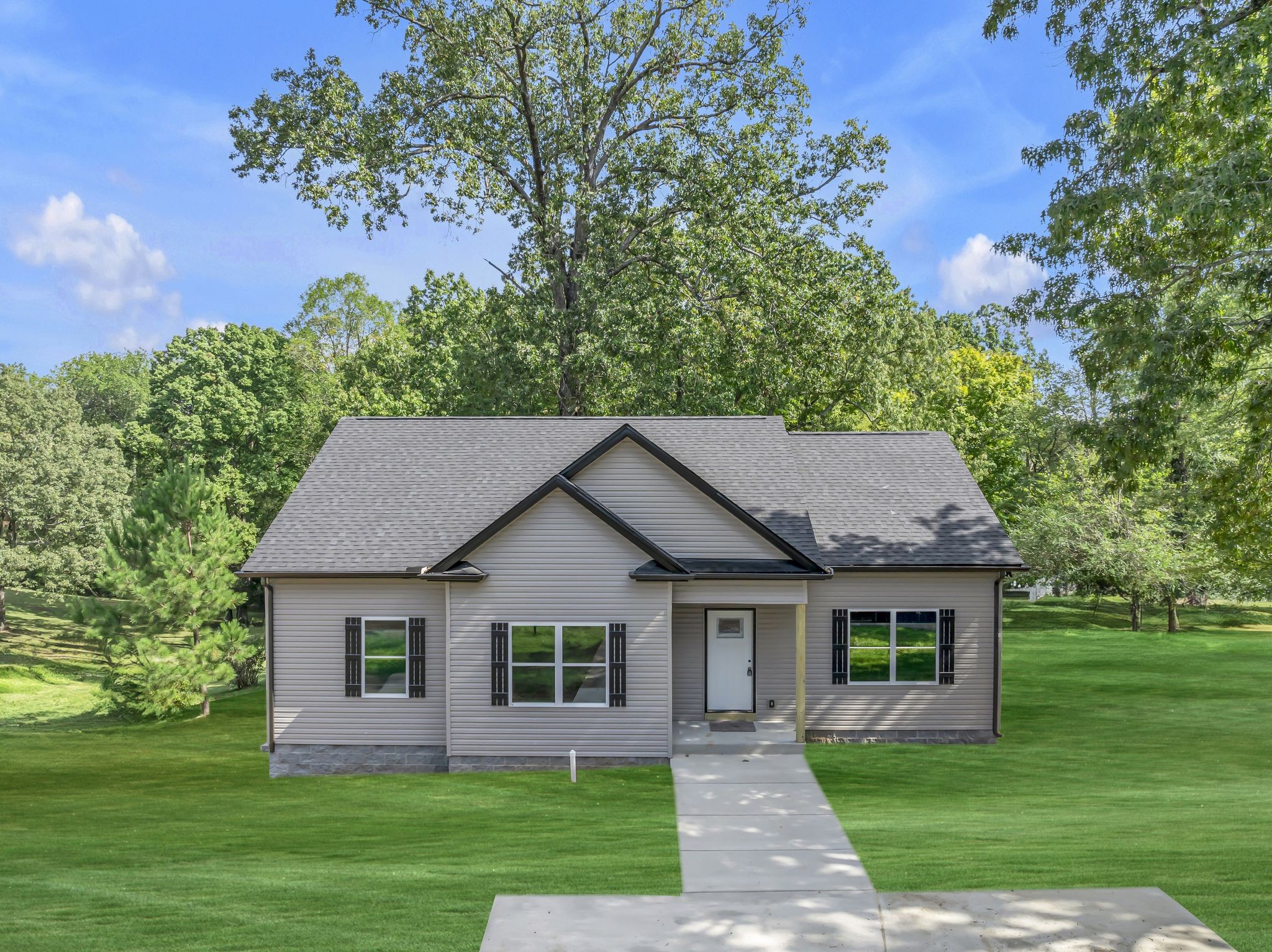 a front view of a house with a yard and green space