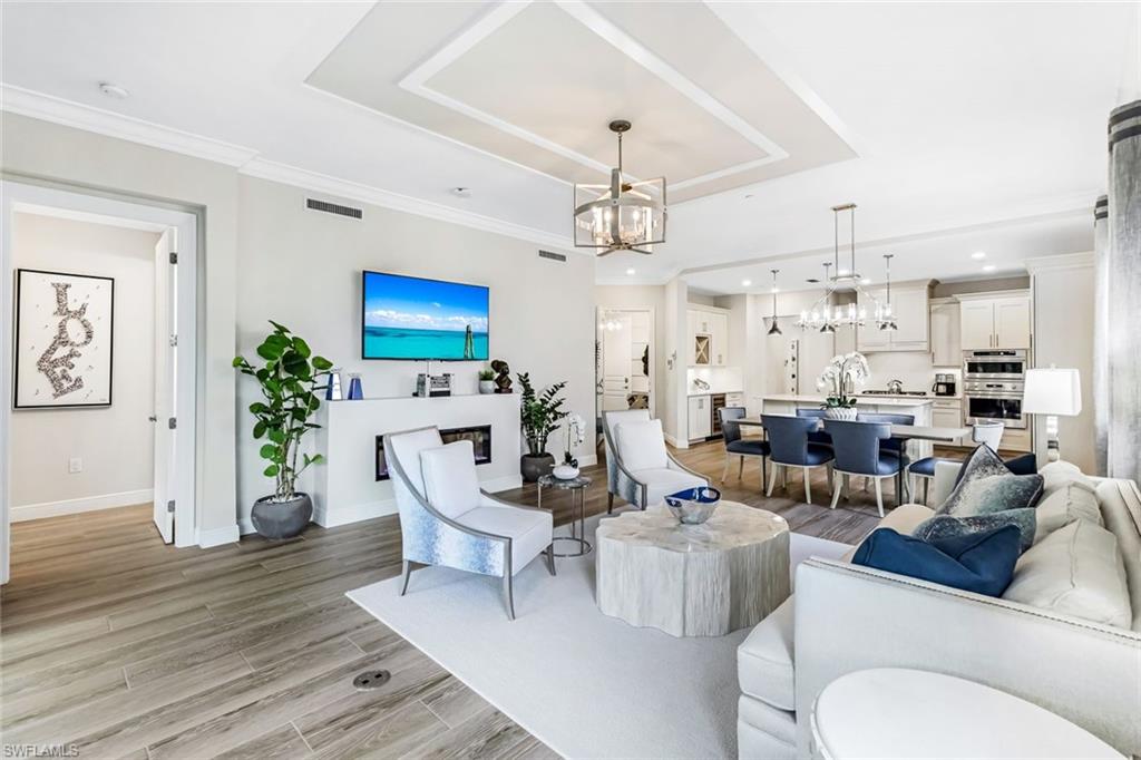 a living room with furniture a chandelier and a wooden floor