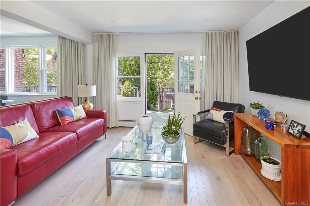 Living room with a baseboard heating unit and light wood-type flooring